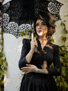 Close up of model wearing the Victorian Dress in Black while holding a matching black parasol.