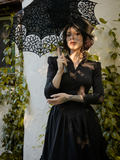 The Victorian Dress in Black being worn be La Femme en Noir model and paired with matching parasol, and black hat.
