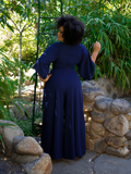 Ashleeta looking away from the camera to show off the back of the Black Widow Palazzo Pants in Navy from La Femme en Noir.