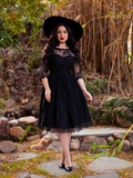 Slightly smiling model wears the gothic glamour inspired Mourning Dress in Black Lace from La Femme Noir.