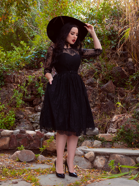 Rachel Sedory adjust the brim of her black sunhat while modeling the Mourning Dress in Black Lace from goth inspired clothier La Femme en Noir.
